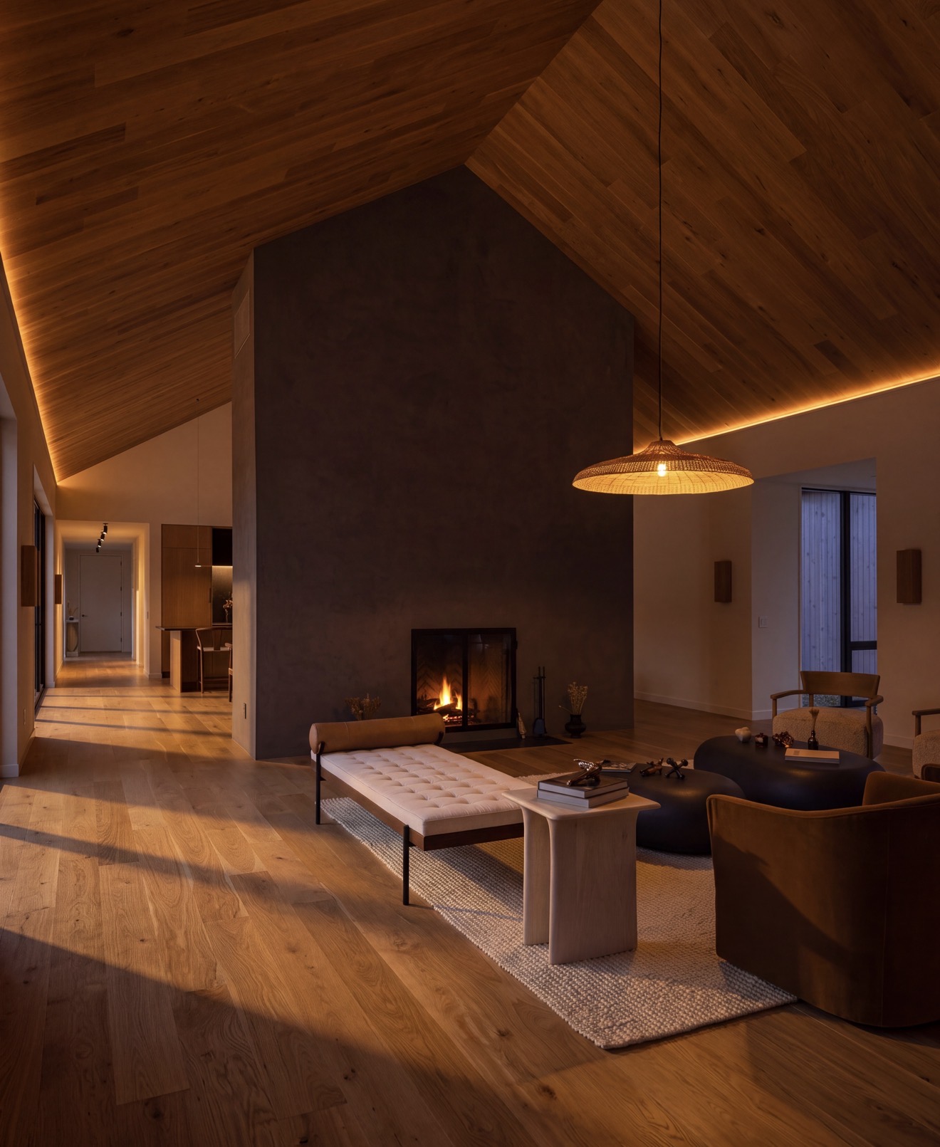 Double-height living space with a central hearth, oak ceiling and warm evening light